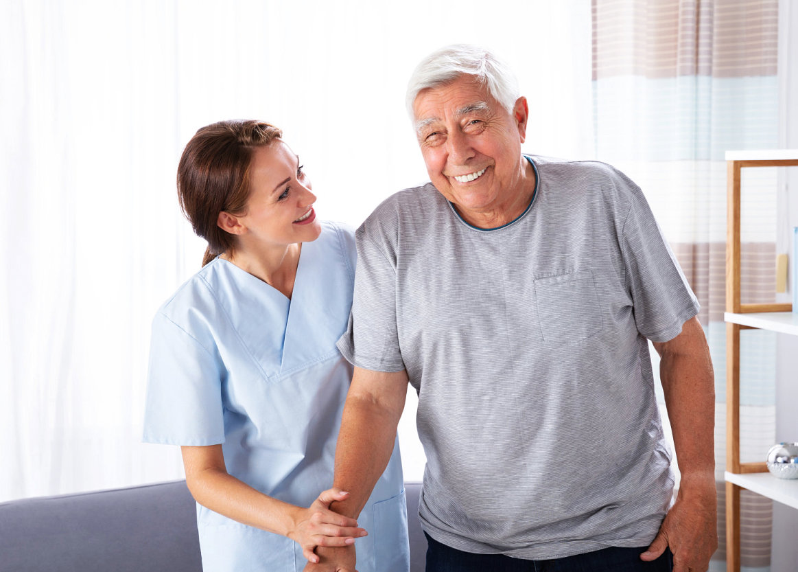 caregiver assisting senior man to stand