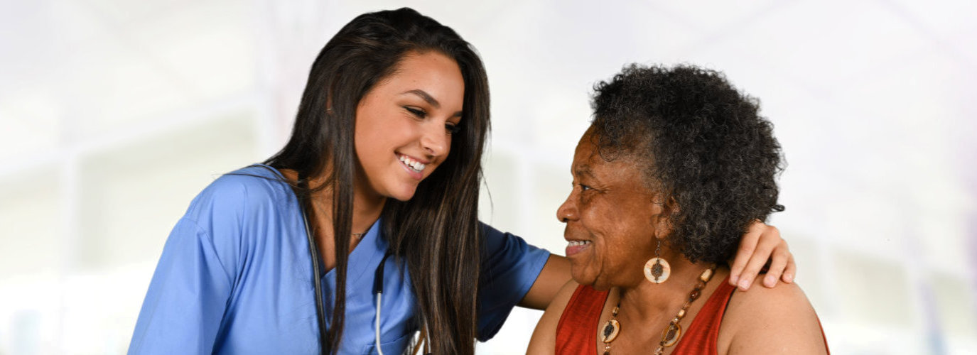 beautiful caregiver smiling at the senior woman